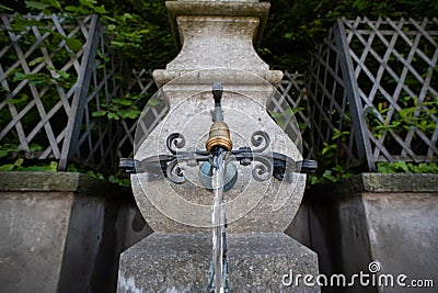 Old stone and metal public drinking water fountain in a city in Switzerland, Europe. Daytime, wide angle, no peop Stock Photo