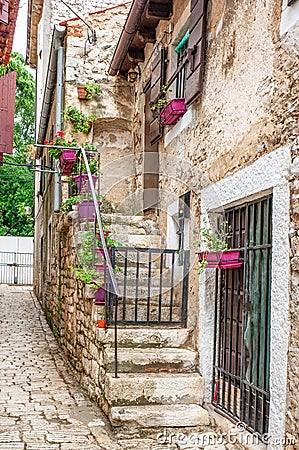 The old stone staircase is decorated with pots of geranium and Petunia flowers in the stone house. European street Stock Photo