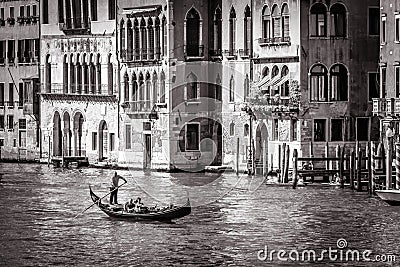 Old street in Venice in black and white. Gondola with tourists sails on Grand Canal Editorial Stock Photo