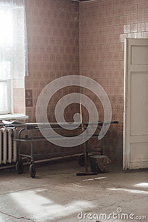 Old stretcher gurney bed in the hospital hallway. Wooden mop bucket and rag. A horrible old hospital or morgue Stock Photo