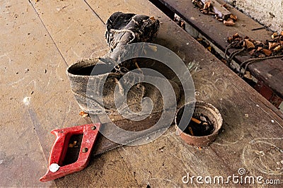 Old sturdy shoes, a strongly rusted saw and an ashtray - Stilllife of forgotten things Stock Photo