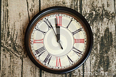 Old style classic clock with roman numbers showing almost twelve o` clock. Time almost gone or came, on wooden texture backgroun Stock Photo