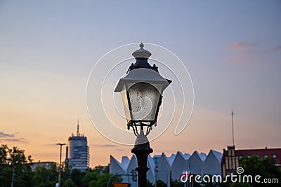 An old style lamp post in focus with the rest of town not in focus in the background as the sun sets over the city of Stettin, Stock Photo