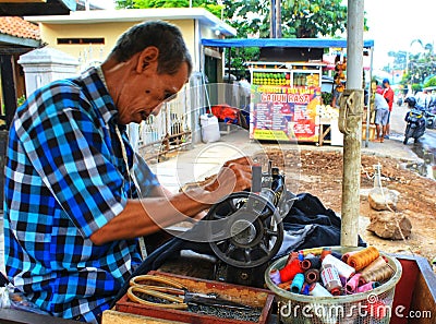 An old tailor sewing pants on the side of the road on a Sunday morning in Ciledug, near Jakarta Indonesia Editorial Stock Photo