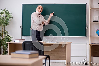 Old male teacher in front of blackboard Stock Photo