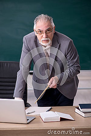 Old male teacher in front of blackboard Stock Photo