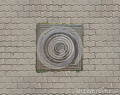 Old teel sewer manhole on the cobblestone road pavement Stock Photo