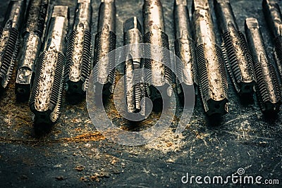 Old tools ,Taps and Dies, Cutting Tools for hand or machine tapping of through or blind holes on rusty metal plate background at Stock Photo