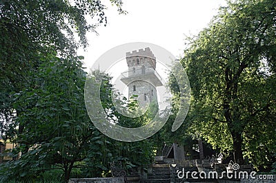 The old tower surrounded by green trees Stock Photo