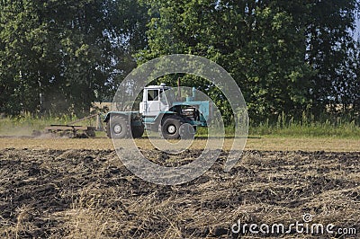 Old tractor ploughs a field after harvesting of the grain 4 Stock Photo