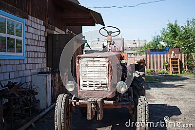 An old tractor in a village courtyard. Close-up Stock Photo