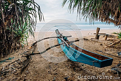 Old tradition Sri Lanka fishermen` boat on the sandy Indian ocean coast between the palm trees near the Weligama, Matara District Stock Photo