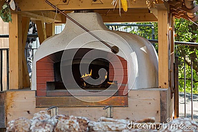 Old traditional stone bread oven stove with burning wood fire an Stock Photo