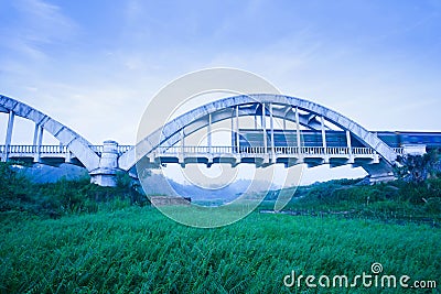 Old train passing the Tha Chomphu Bridge in blue misty morning, the ancient railway bridge of Thailand Stock Photo