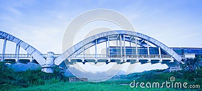 Old train passing the Tha Chomphu Bridge in blue misty morning, the ancient railway bridge of Thailand Stock Photo