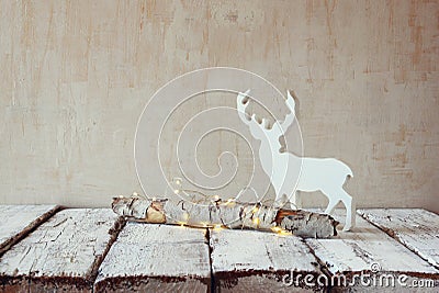 Old tree log with fairy christmas lights and reindeer on wooden table.selective focus Stock Photo