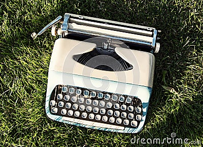 Old turquoise typewriter on the grass Stock Photo