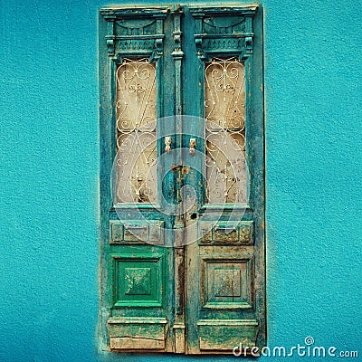 Old turquoise wooden door on blue wall with copy space. Texture background. Pop art concept, vintage style. Square crop Stock Photo