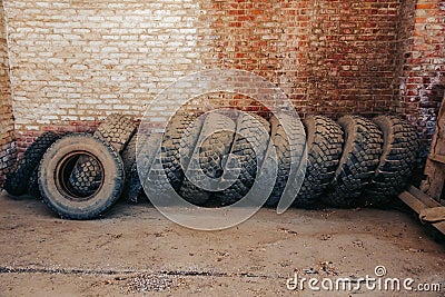 Old used truck tires stand against the wall in the garage Stock Photo