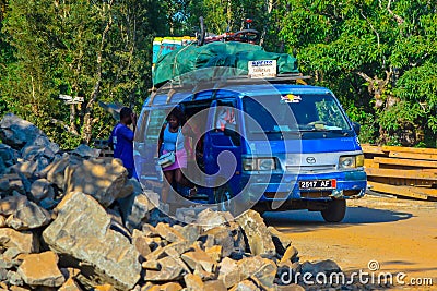 An old vehicle with a luggage on the roof, street view in Madagascar`s dirt road, people get out of public transport Editorial Stock Photo