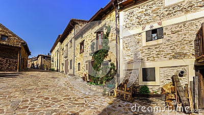 Old village street with stone houses and firewood at the door for the winter. La Hiruela Madrid Stock Photo