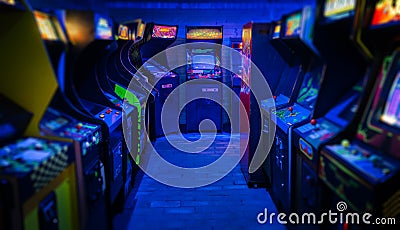 Old Vintage Arcade Video Games in an empty dark gaming room with blue light with glowing displays Stock Photo