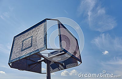 Old and vintage basketball backboard and hoop. Basketball hoop on a background of blue sky and white clouds. Stock Photo