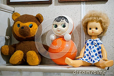 Old vintage childrens toys - a doll, a bear and a tumbler on a mantelpiece Stock Photo