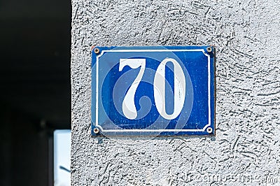 Old vintage house address metal number 70 seventy on the plaster facade of abandoned home exterior wall on the street side Stock Photo