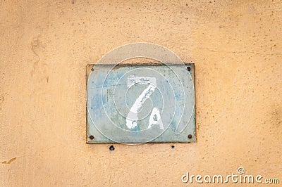 Old vintage house address metal plate number 7 A seven on the plaster facade of abandoned home exterior wall on the street side Stock Photo