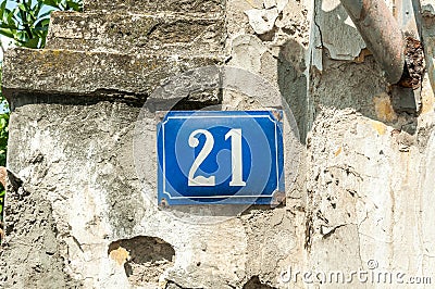 Old vintage house address metal plate number 21 twenty-one on the plaster facade of abandoned home exterior wall on the street s Stock Photo