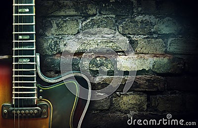 Old vintage jazz guitar on a brick wall background. Copy space. Background for concerts, festivals, music schools. Art Stock Photo