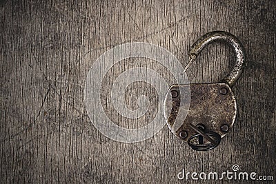 Old vintage lock with key. Ancient rusty barn lock with key on wooden textured background. Stock Photo