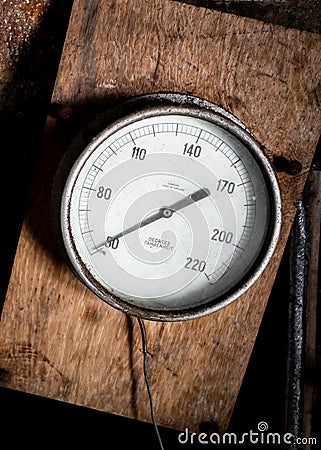 Old vintage metal degrees Fahrenheit instrument gauge meter dial to measure heat temperature attached to wood with retro needle Stock Photo