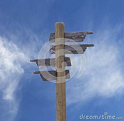 Old wooden road sign with four arrows over sky Stock Photo