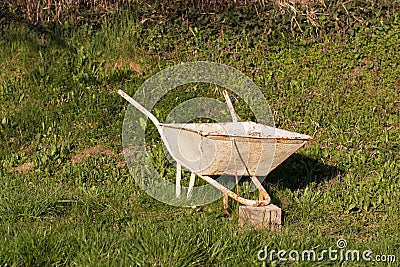 Old vintage wheelbarrow on a green grass in a garden. Stock Photo