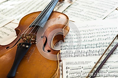 Old violin lying on the sheet of music Stock Photo
