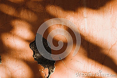An old wall with orange cracks. Plaster is falling off.Shadows fall on the wall Stock Photo