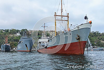 Old warships of the Russian Navy in the port of Sevastopol on the background of gray sky. Editorial Stock Photo