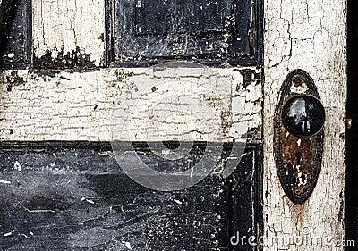 Old weathered antique beat-up wood panel door with chipped peeling paint and black porcelain doorknob and rusty plate Stock Photo