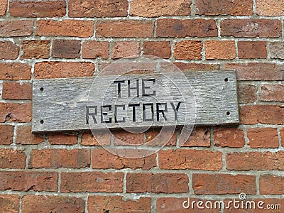 Old weathered wooden Rectory sign on a brick wall Stock Photo