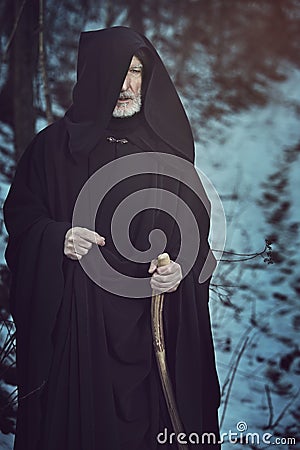 Old white beard pilgrim in dark forest with snow Stock Photo