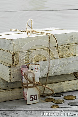 Old white books with money and coins on wooden background Stock Photo