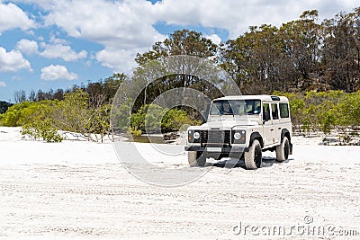 Old white coloured four-wheel drive off-road vehicle standing on a beach on the west coast of Fraser Island, Queensland. Stock Photo