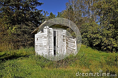 Old white outhouse in the woods Stock Photo