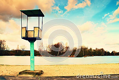 Old white and rusty metal lifeguard tower with chair on a beach. Frozen water level within witer Stock Photo