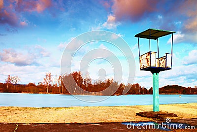 Old white and rusty metal lifeguard tower with chair on a beach. Frozen water level within witer Stock Photo