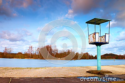 Old white and rusty metal lifeguard tower with chair on a beach. Frozen water level within witer Stock Photo