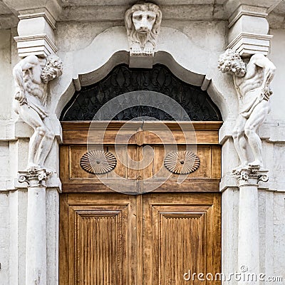 Old white stone entrance with statues and wooden portal. Stock Photo