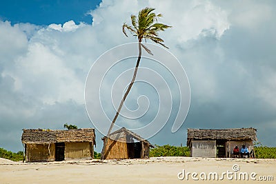 Old wicker African huts and palms on the ocean Editorial Stock Photo